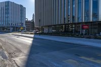 an empty street in front of tall buildings and a pot hole on the street corner