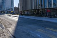 an empty street in front of tall buildings and a pot hole on the street corner