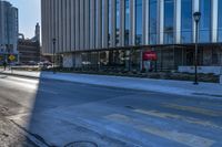 an empty street in front of tall buildings and a pot hole on the street corner