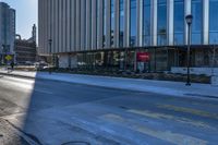 an empty street in front of tall buildings and a pot hole on the street corner