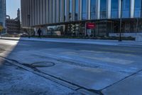 an empty street in front of tall buildings and a pot hole on the street corner