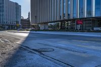 an empty street in front of tall buildings and a pot hole on the street corner