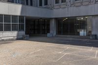 a person on a skate board riding across an empty walkway in front of a building