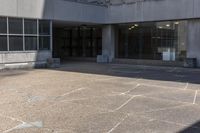 a person on a skate board riding across an empty walkway in front of a building