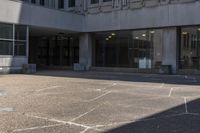 a person on a skate board riding across an empty walkway in front of a building