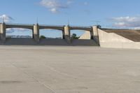 a person is riding their skate board on the concrete surface at the edge of a dam