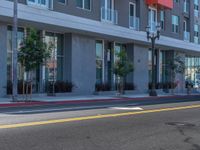 an empty street next to a tall building that has green doors on it, and yellow markings