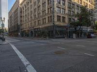 cars drive down the street in front of the tall building with glass windows on the third story