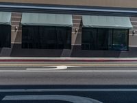 a street with white lines that look like a road sign pointing to an intersection where two buildings, one with large windows, are reflected in the sun