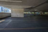 the view of an empty building from inside a parking garage area with columns and concrete walls