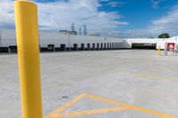 a large storage building under a cloudy blue sky with yellow painted lines around the entrance