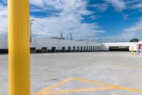 a large storage building under a cloudy blue sky with yellow painted lines around the entrance