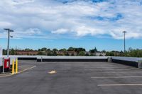 an empty parking lot with many lights and some trees in the distance, near a large building