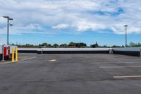 an empty parking lot with many lights and some trees in the distance, near a large building