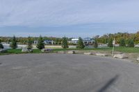 a paved parking lot in a park with benches and tree lined trees surrounding it with blue sky in the background