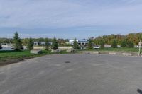 a paved parking lot in a park with benches and tree lined trees surrounding it with blue sky in the background