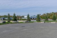 a paved parking lot in a park with benches and tree lined trees surrounding it with blue sky in the background