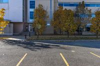 a building sitting next to a parking lot near trees and grass, with two fire hydrants on the sidewalk in between