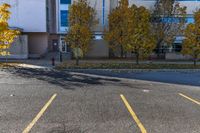 a building sitting next to a parking lot near trees and grass, with two fire hydrants on the sidewalk in between