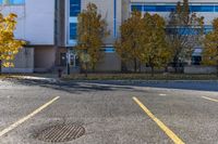 a building sitting next to a parking lot near trees and grass, with two fire hydrants on the sidewalk in between