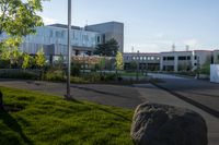 a city street surrounded by grass and tall buildings at the end of a street there is a paved pathway in front of the building