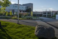 a city street surrounded by grass and tall buildings at the end of a street there is a paved pathway in front of the building