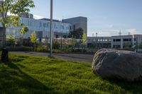 a city street surrounded by grass and tall buildings at the end of a street there is a paved pathway in front of the building