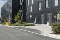 some grey buildings and black plants near the street and sky behind them with a white border