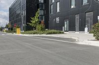 some grey buildings and black plants near the street and sky behind them with a white border