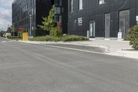 some grey buildings and black plants near the street and sky behind them with a white border