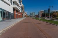 an empty street is pictured on the sidewalk outside of a building in the background, a parking meter and lots of glass