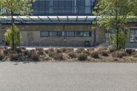 an empty building with trees in front of it in the daytime sun next to a street