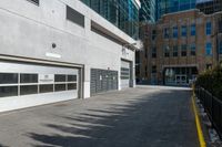 a concrete street with a building in the back and doors at one end of it