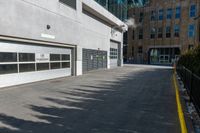 a concrete street with a building in the back and doors at one end of it