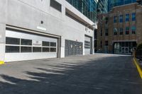 a concrete street with a building in the back and doors at one end of it