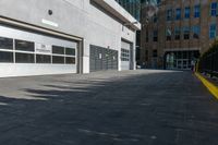 a concrete street with a building in the back and doors at one end of it