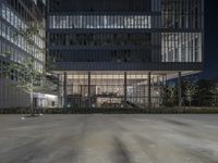 an empty parking lot with a building in the background at night with street lamps on