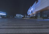 a night shot of a parking area with cars and buildings lit up in blue lights