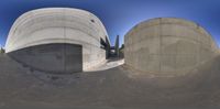 two circular concrete shapes, with a ramp, a building and an empty area in the back ground