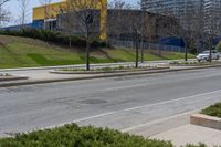 an empty street next to tall buildings on the side of the road with trees near by