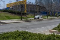 an empty street next to tall buildings on the side of the road with trees near by