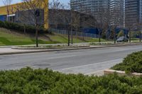 an empty street next to tall buildings on the side of the road with trees near by