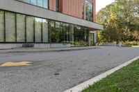 an empty road with a person walking on it next to buildings and trees in the background