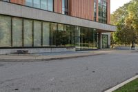 an empty road with a person walking on it next to buildings and trees in the background