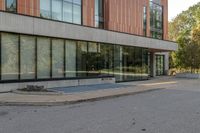 an empty road with a person walking on it next to buildings and trees in the background