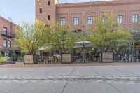 an empty cobblestone walkway at an outdoor restaurant and patio area in front of brick buildings