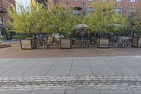 an empty cobblestone walkway at an outdoor restaurant and patio area in front of brick buildings