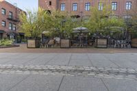 an empty cobblestone walkway at an outdoor restaurant and patio area in front of brick buildings