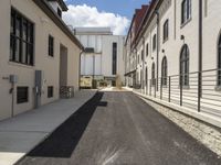 an empty sidewalk in between two very wide buildings and a few people walking around the corner