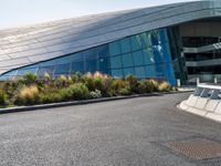 a large white building with a glass facade near the road of grass and bushes with metal trim